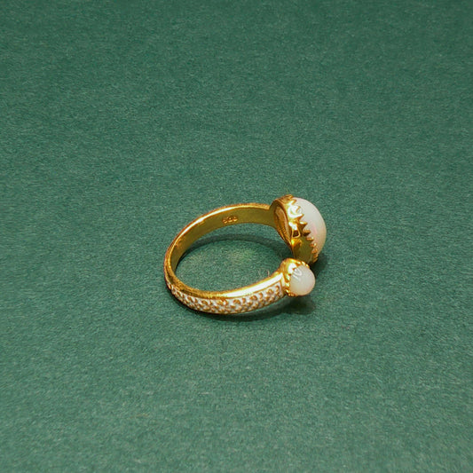 Gold ring with pearl accents on a green background