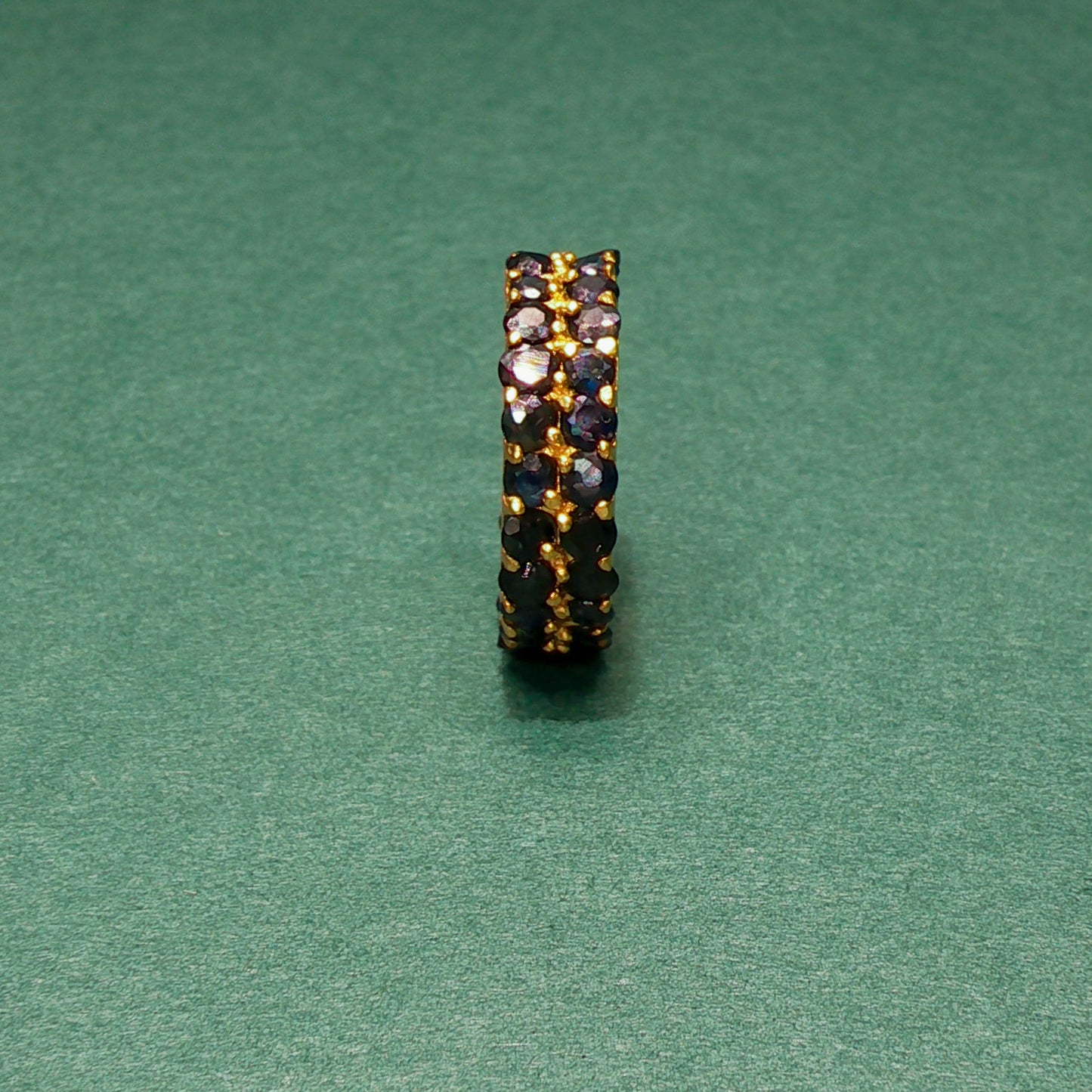 Jewelry ring with embedded stones on a green background

