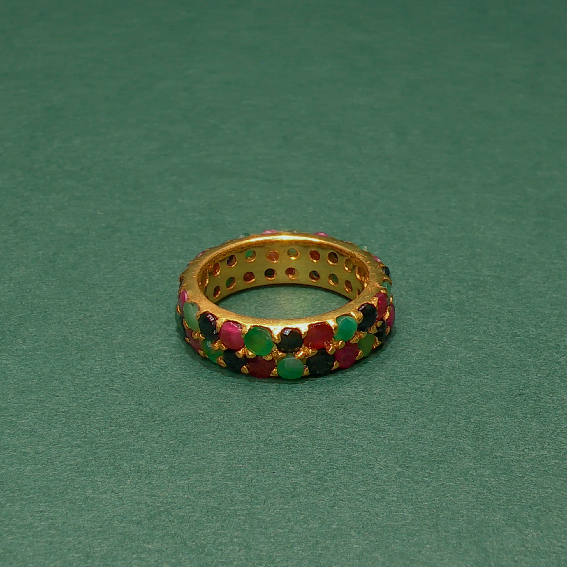 Gold ring with colorful gemstones on a green background