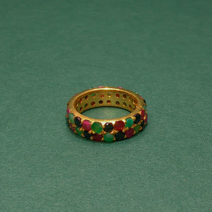 Gold ring with colorful gemstones on a green background