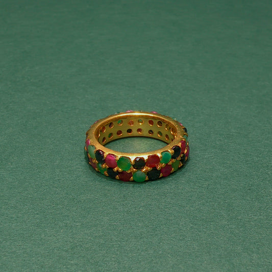 Gold ring with colorful gemstones on a green background