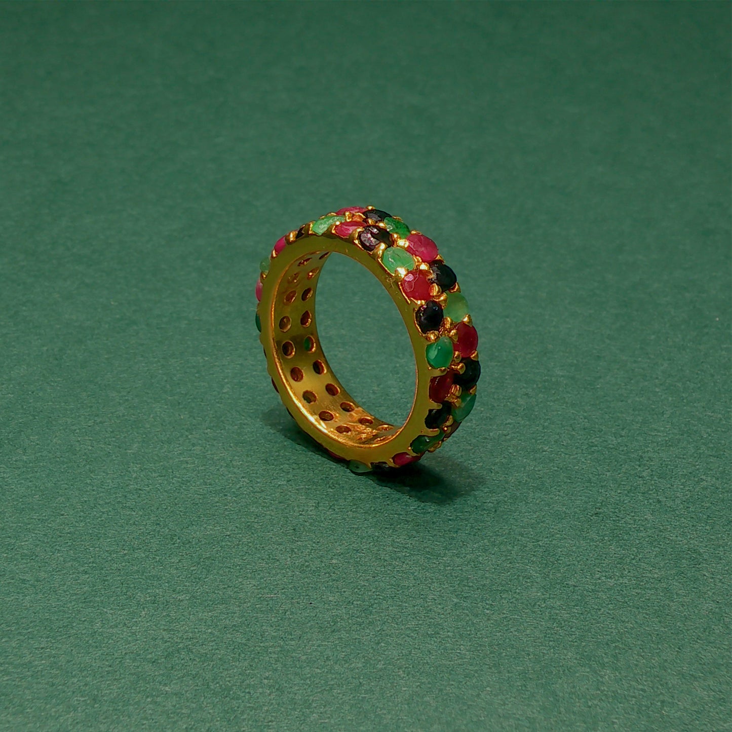 Gold ring with colorful gemstones on a green background