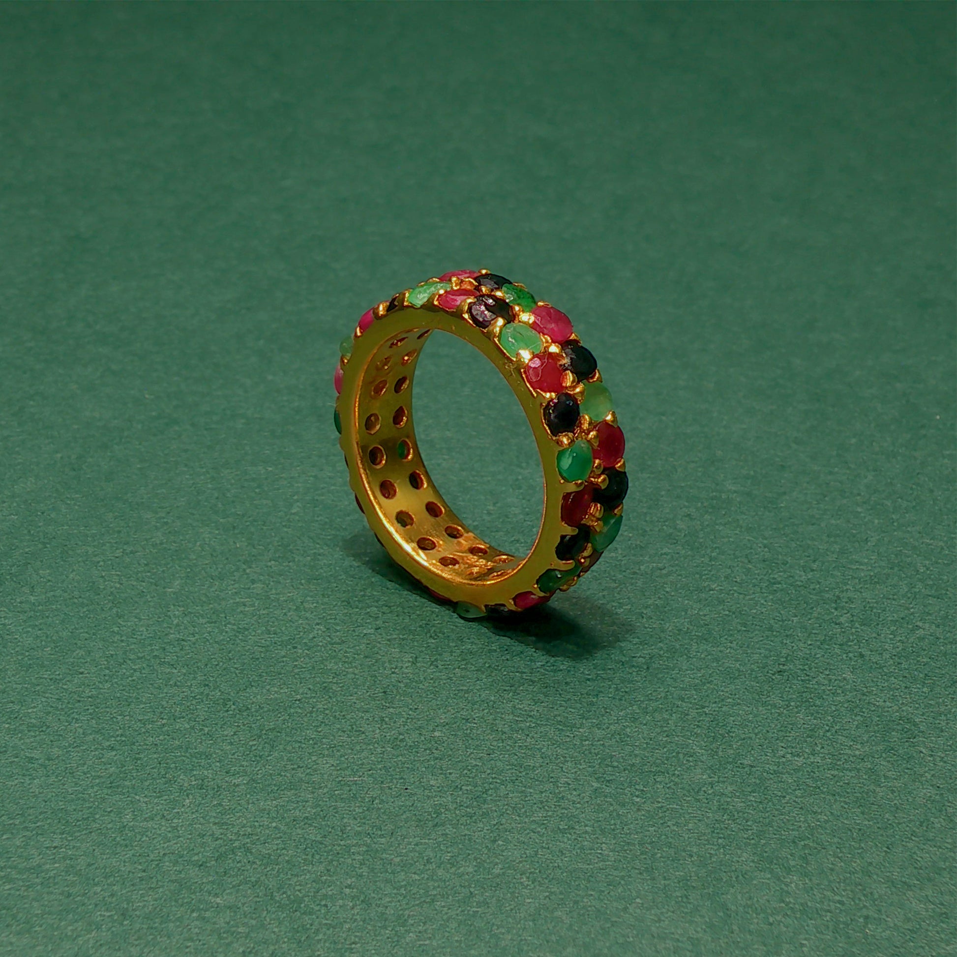 Gold ring with colorful gemstones on a green background