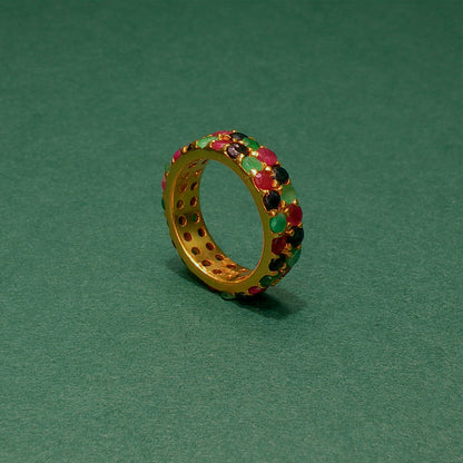 Gold ring with colorful gemstones on a green background