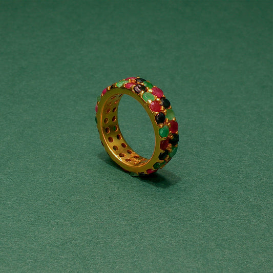 Gold ring with colorful gemstones on a green background