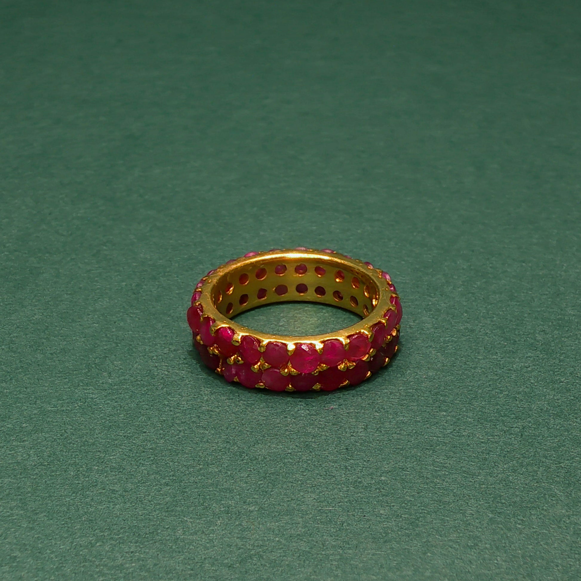 Gold ring with red gemstones on a green background