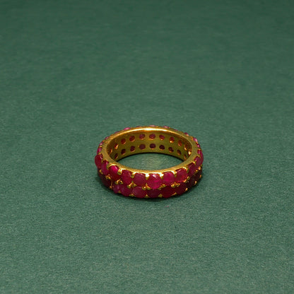 Gold ring with red gemstones on a green background
