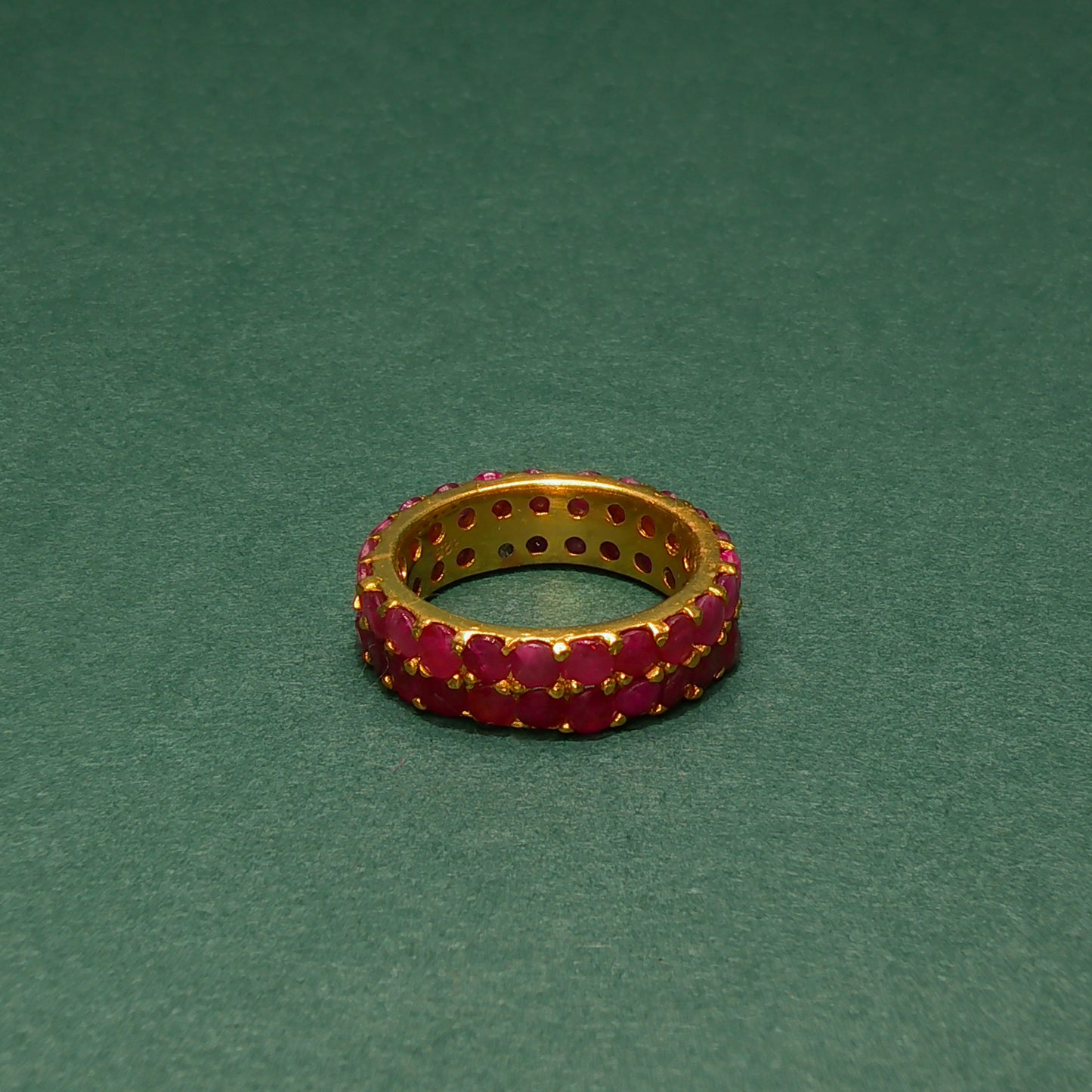 Gold ring with red gemstones on a green background
