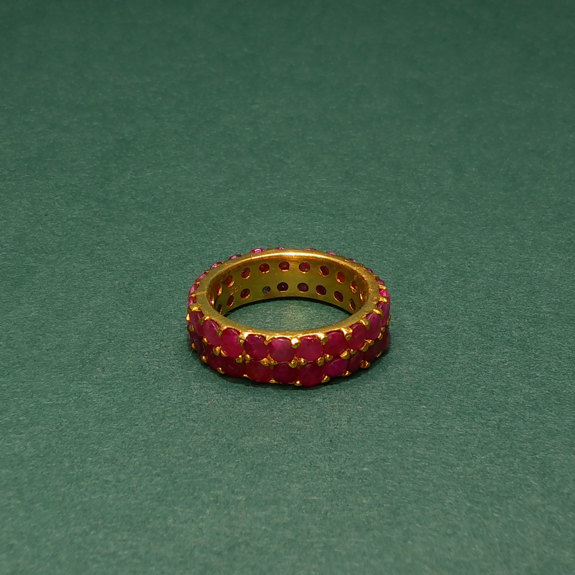 Gold ring with red gemstones on a green background