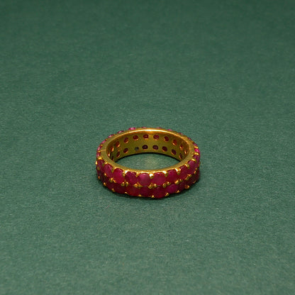 Gold ring with red gemstones on a green background
