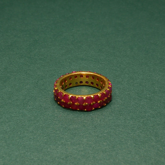 Gold ring with red gemstones on a green background