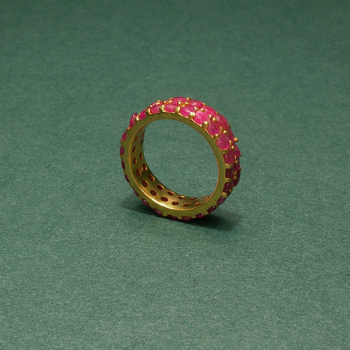 Gold ring with pink gemstones on a green background