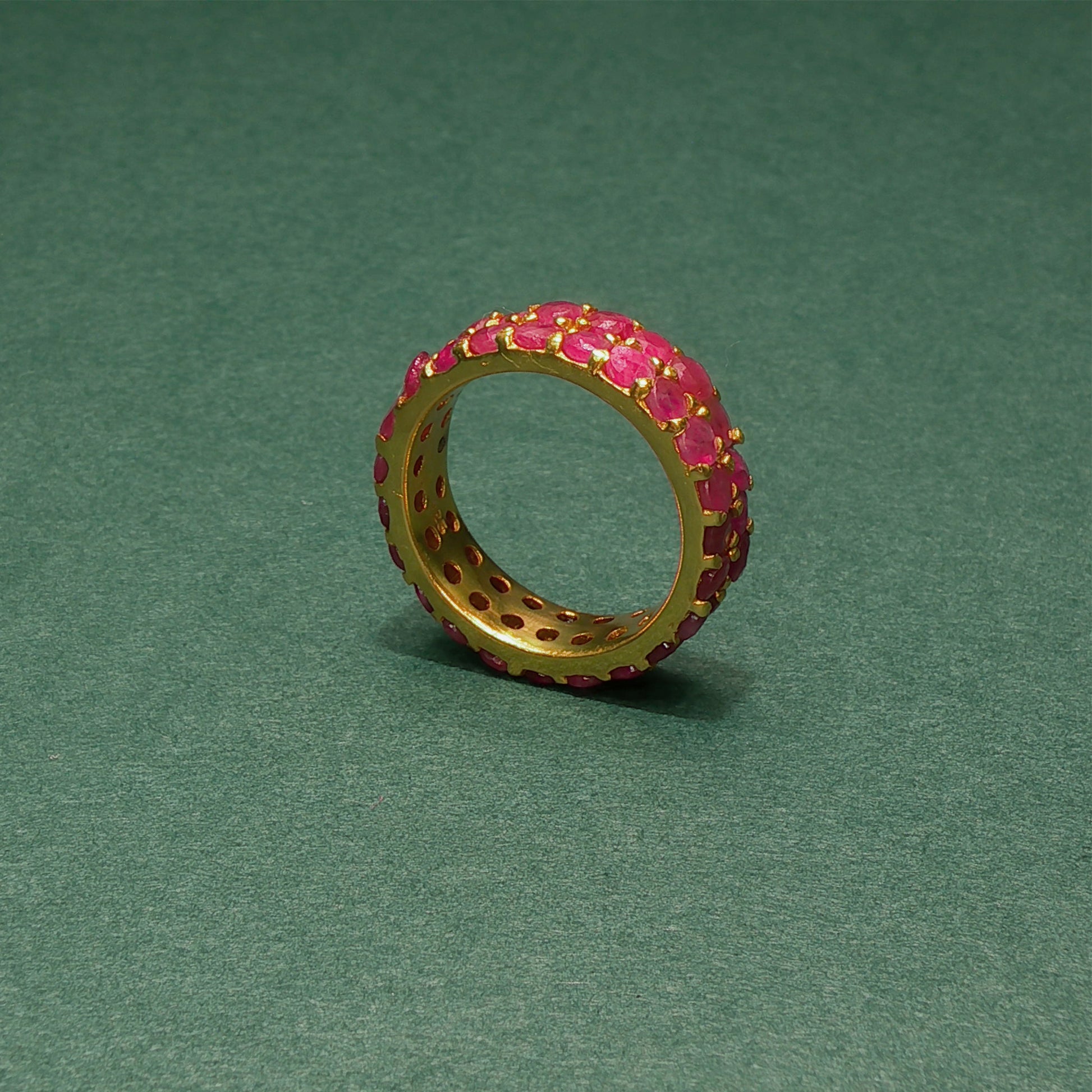 Gold ring with pink gemstones on a green background