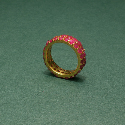 Gold ring with pink gemstones on a green background
