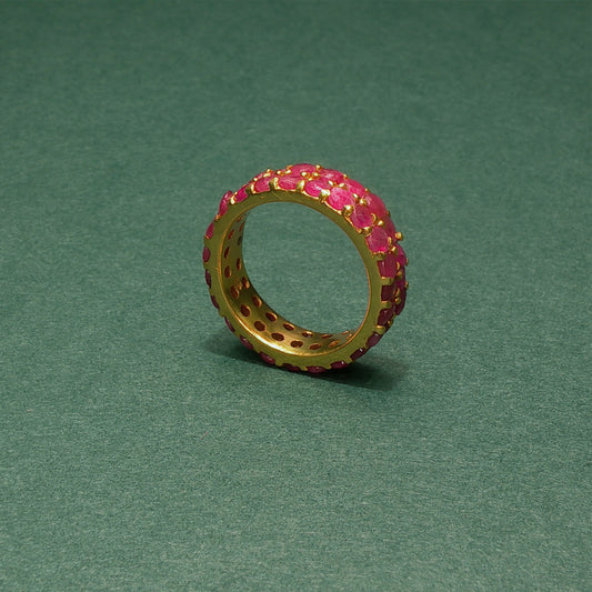 Gold ring with pink gemstones on a green background