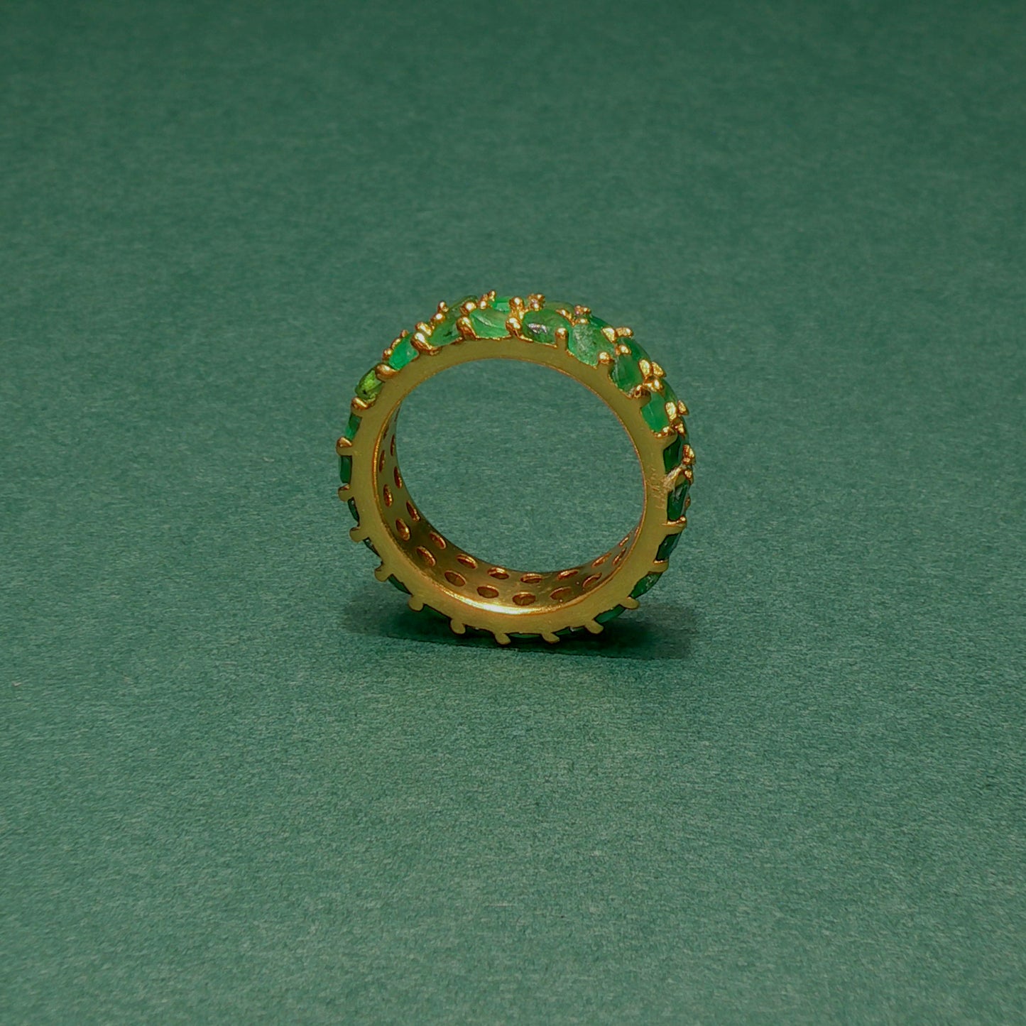 Gold ring with green gemstones on a green background