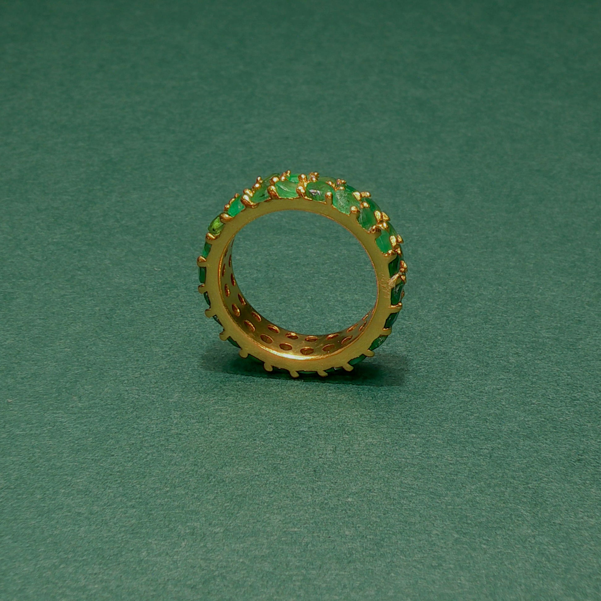 Gold ring with green gemstones on a green background
