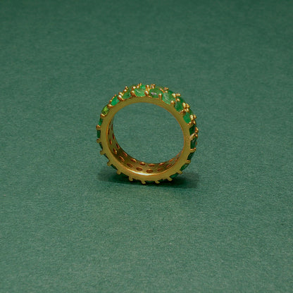 Gold ring with green gemstones on a green background