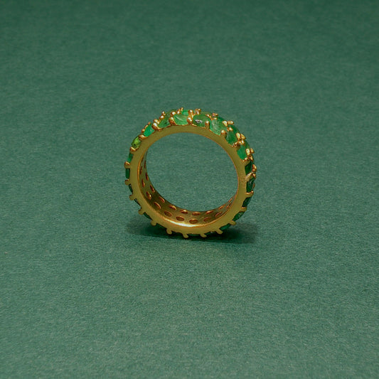 Gold ring with green gemstones on a green background