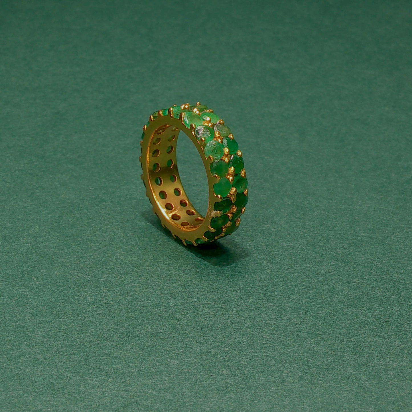 Gold ring with green gemstones on a green background