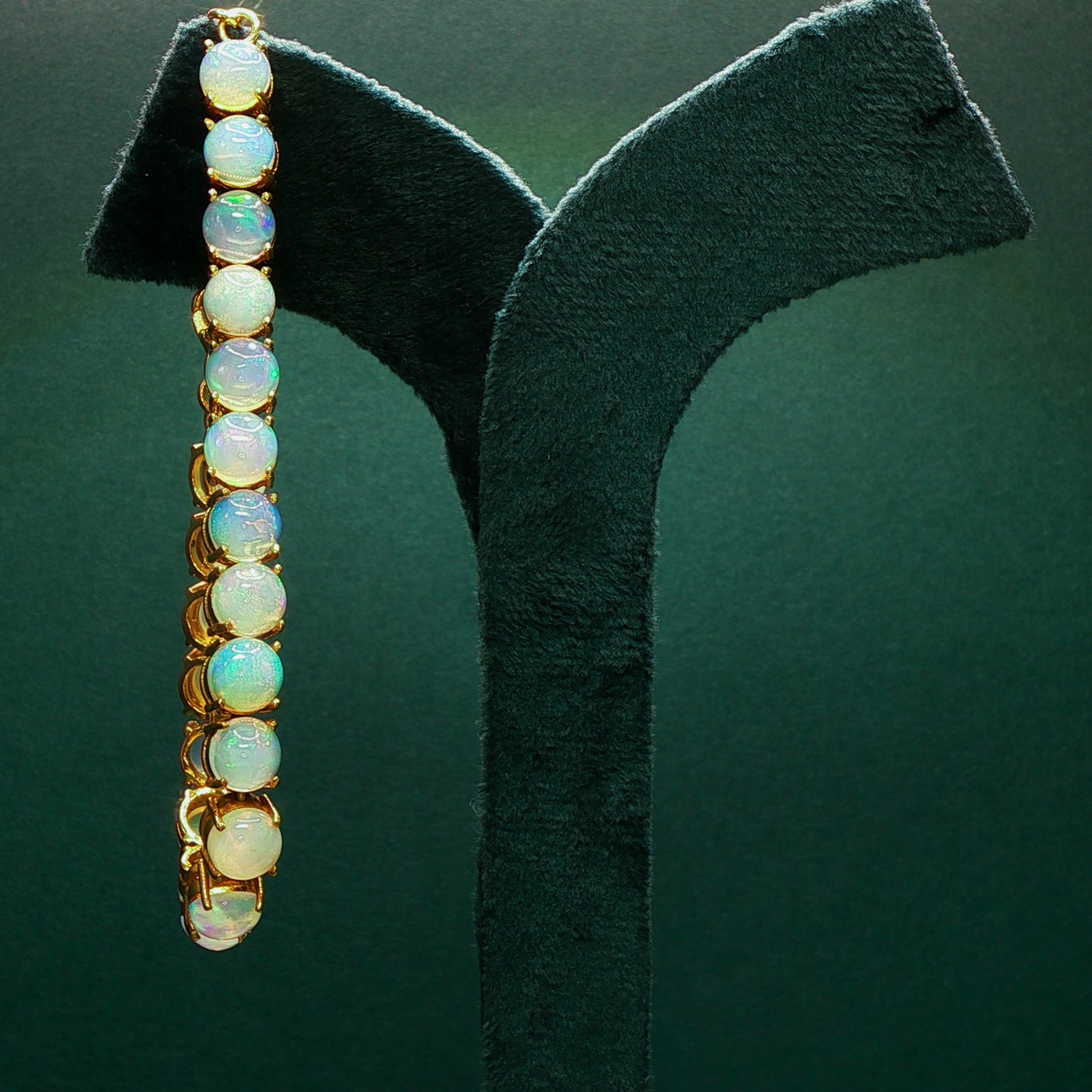 Opal earrings on a black stand against a green background