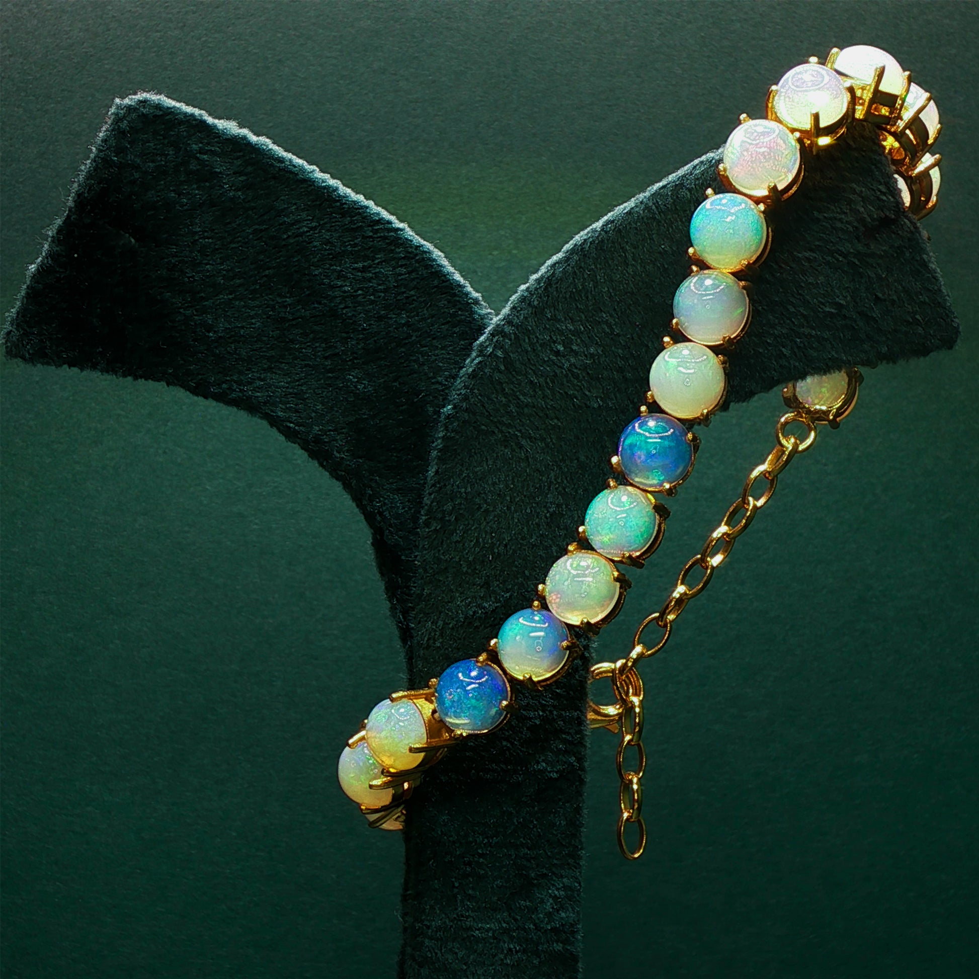 Opal earring on a black stand with a green background