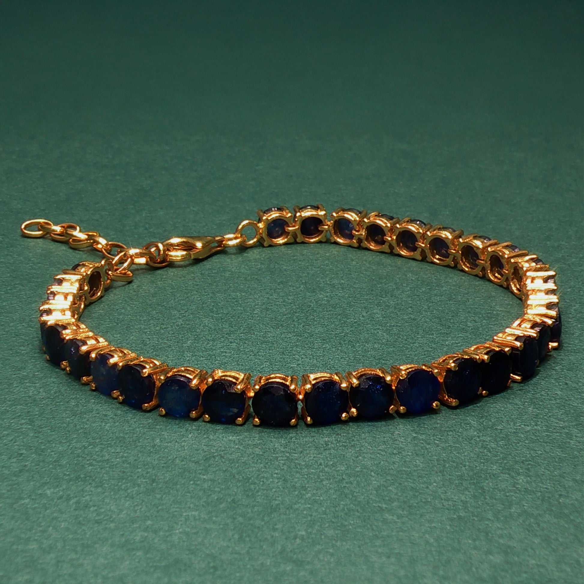 Gold bracelet with blue stones on a green background