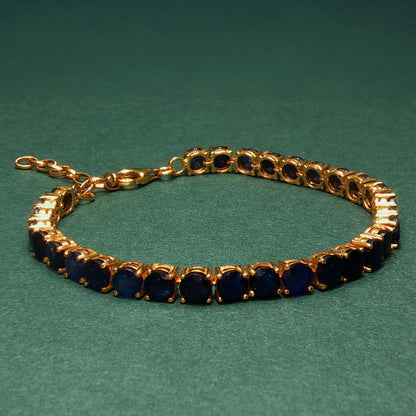 Gold bracelet with blue stones on a green background