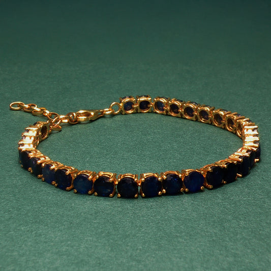 Gold bracelet with blue stones on a green background
