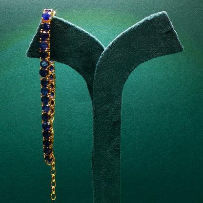 Gold bracelet with blue stones on a green stand