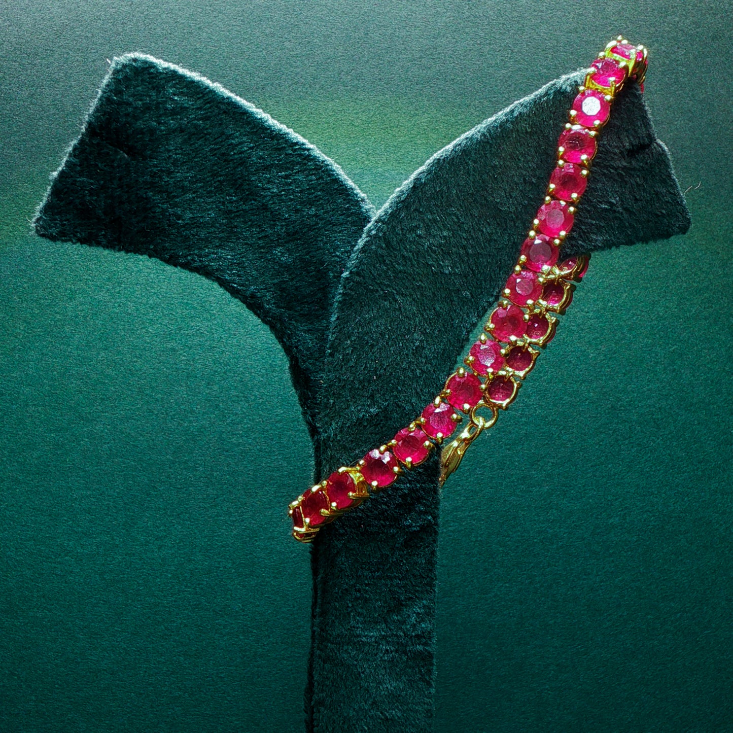 silver bracelet with red gemstones on a green stand

