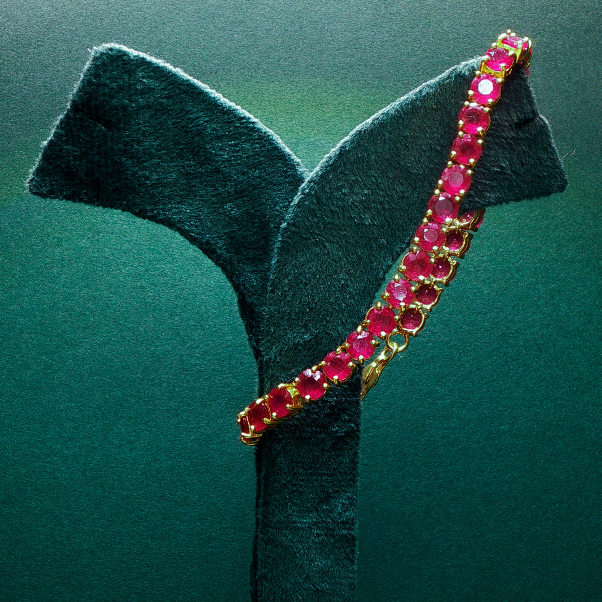 silver bracelet with red gemstones on a green stand

