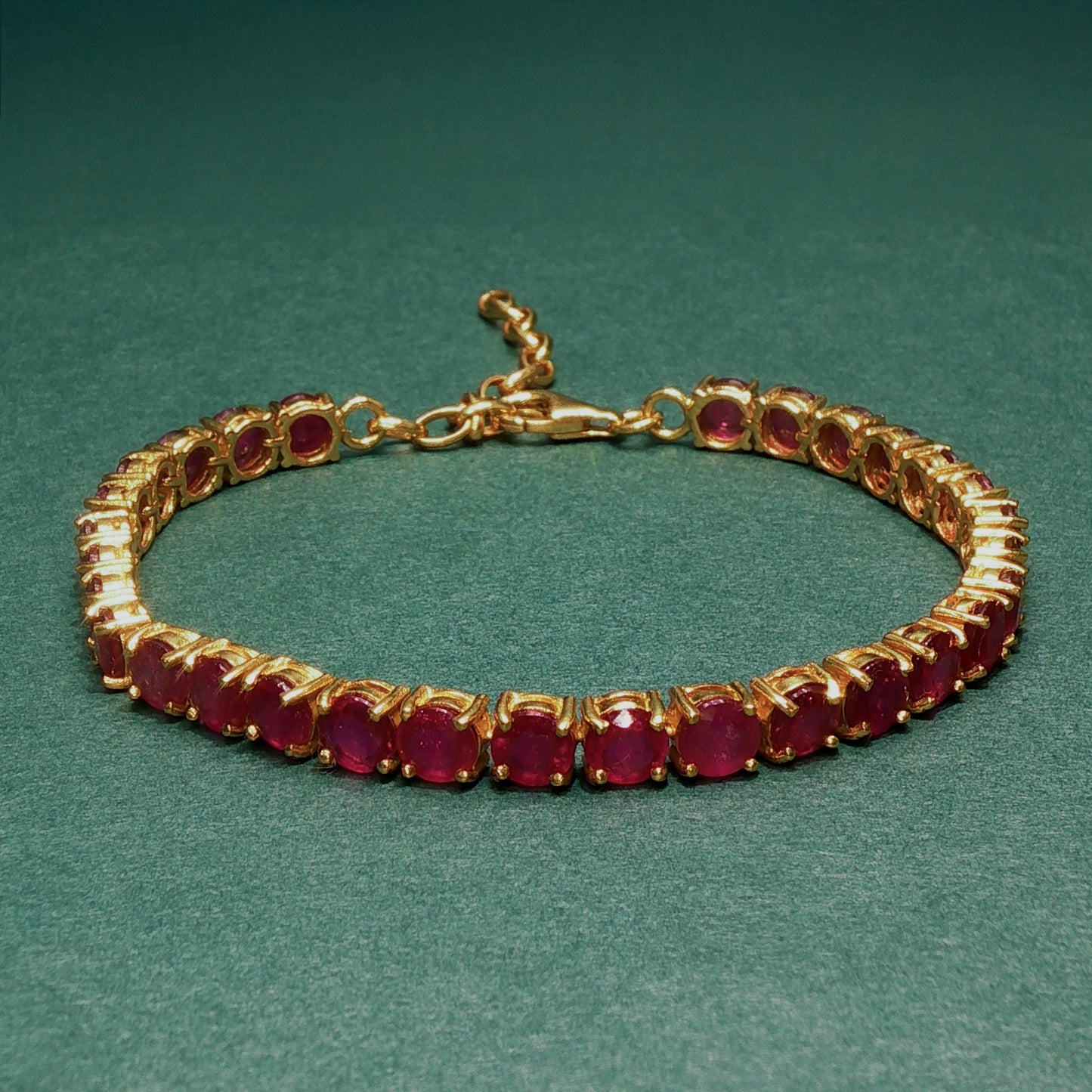 Gold bracelet with red gemstones on a green background