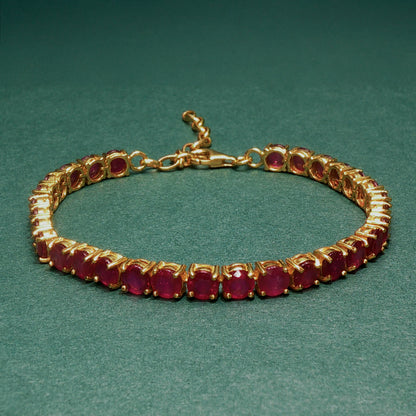 Gold bracelet with red gemstones on a green background