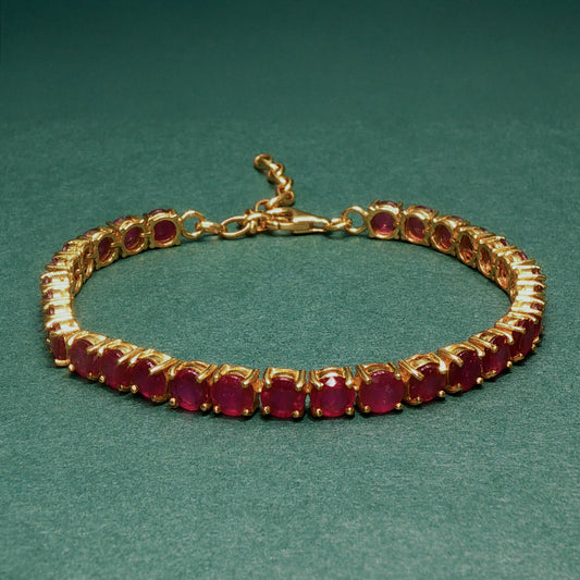 Gold bracelet with red gemstones on a green background