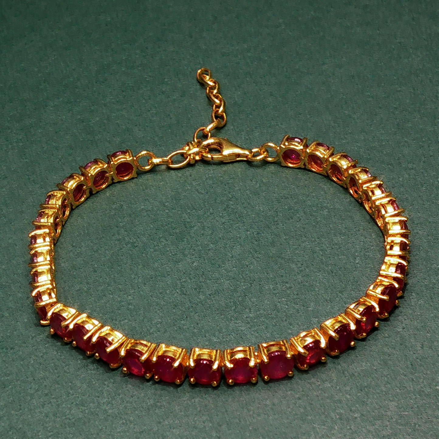 Gold bracelet with red gemstones on a green background