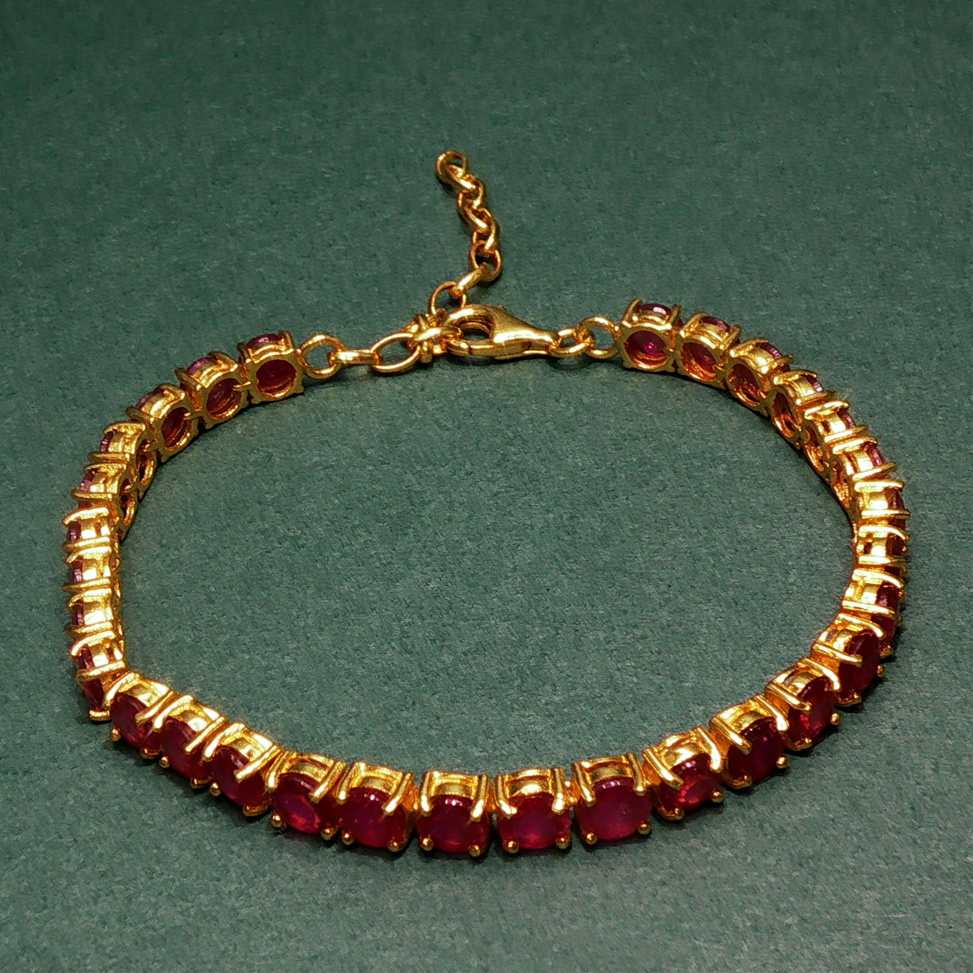 Gold bracelet with red gemstones on a green background