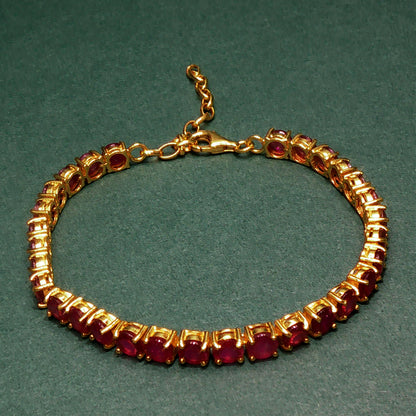 Gold bracelet with red gemstones on a green background