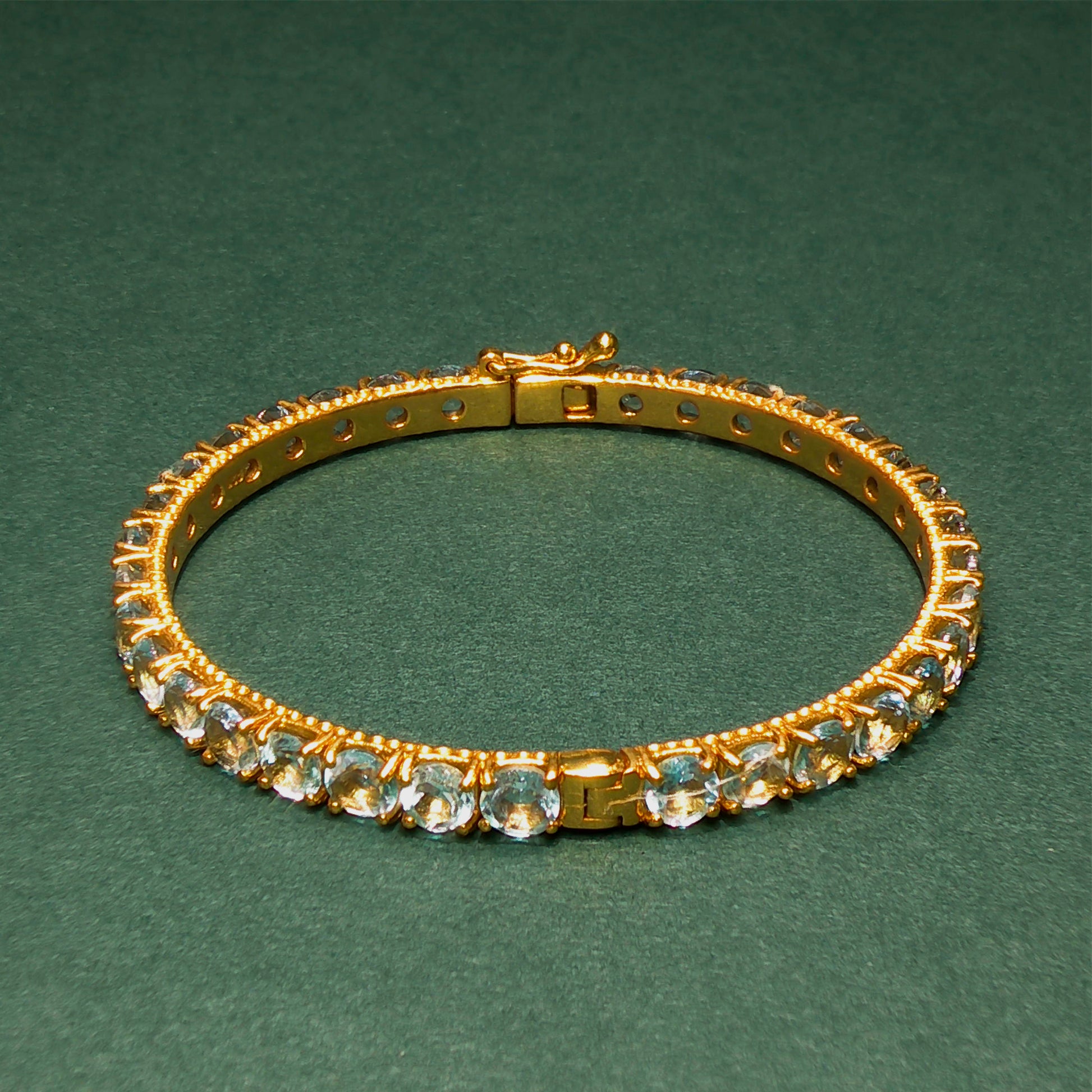 Gold bracelet with gemstones on a green background

