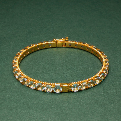 Gold bracelet with gemstones on a green background

