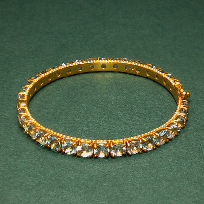 Gold bracelet with gemstones on a green background

