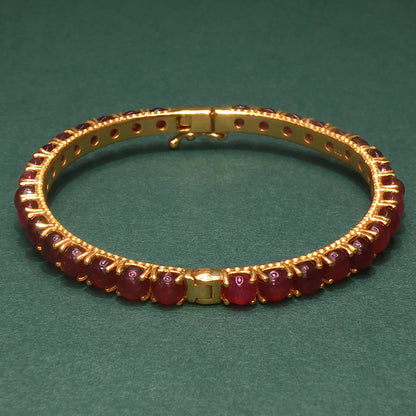 Gold bracelet with gemstones on a green background

