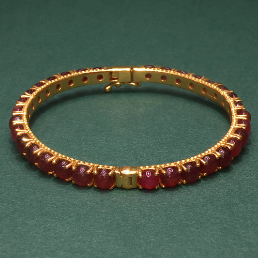 Gold bracelet with gemstones on a green background

