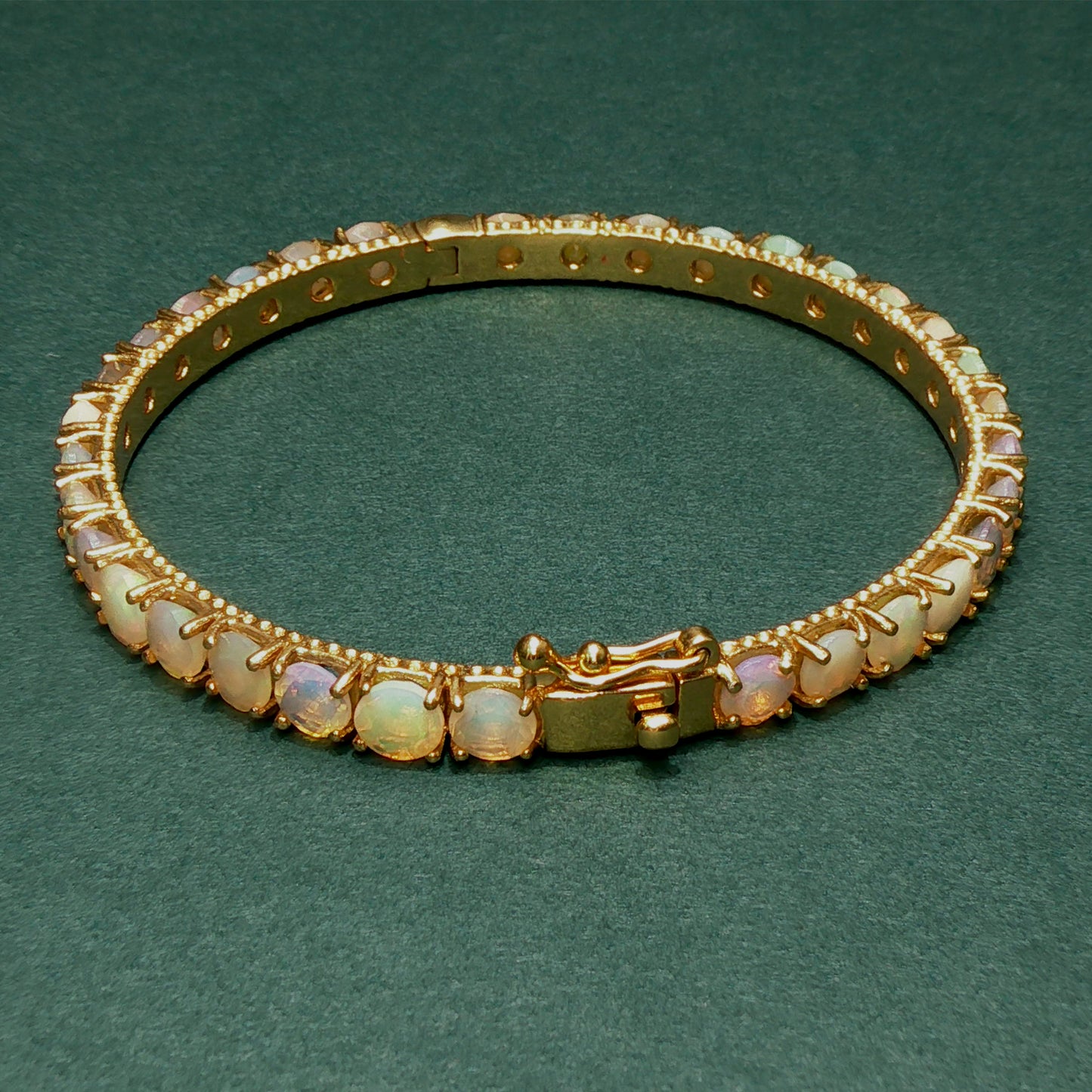 Gold bracelet with opal stones on a green background

