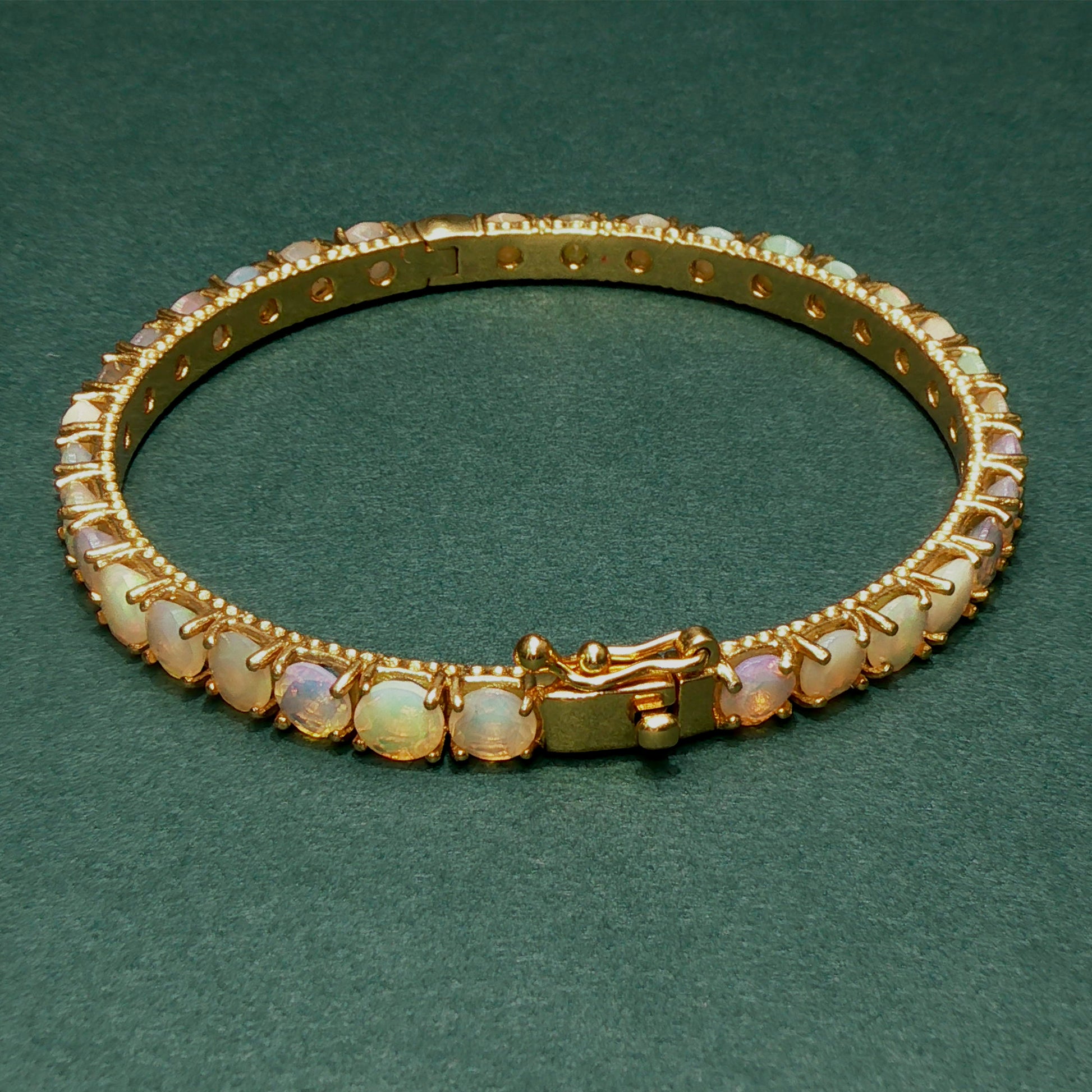 Gold bracelet with opal stones on a green background

