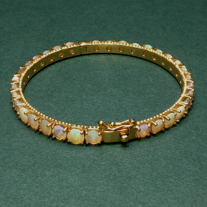 Gold bracelet with opal stones on a green background

