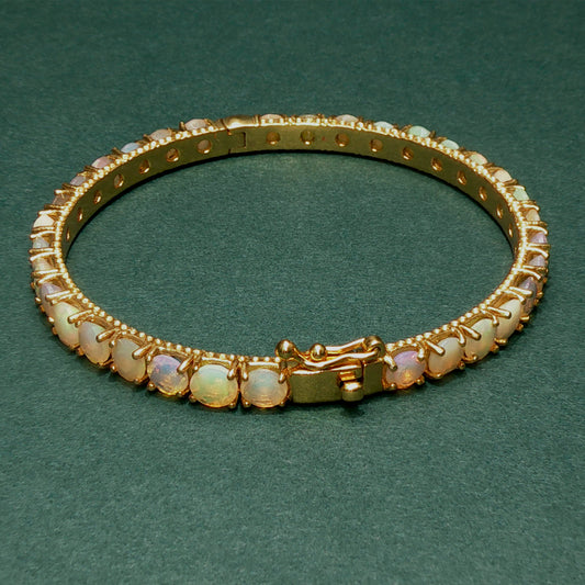 Gold bracelet with opal stones on a green background

