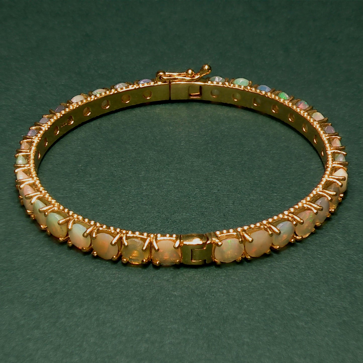 silver bracelet with gemstones on a green background

