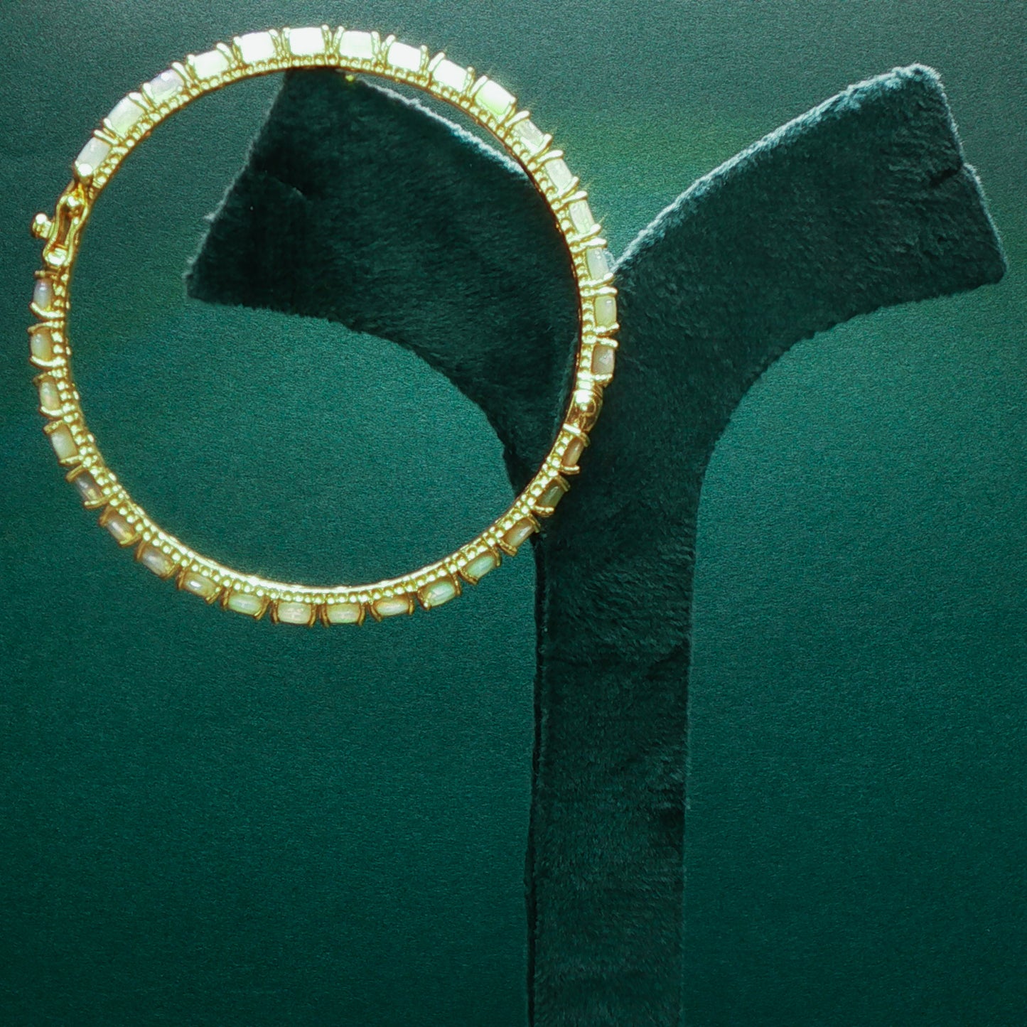 silver hoop earring with embedded stones on a green stand

