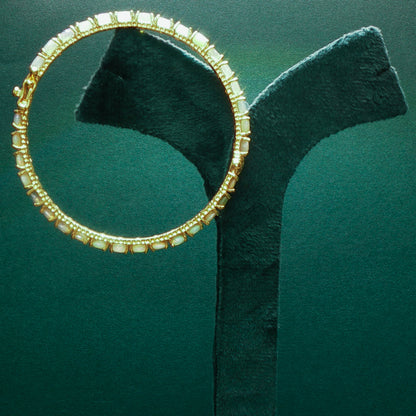 silver hoop earring with embedded stones on a green stand

